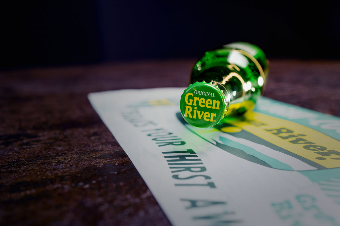 An Irish Shandy cocktail with bottles of Green River and Abbey Triple in the background