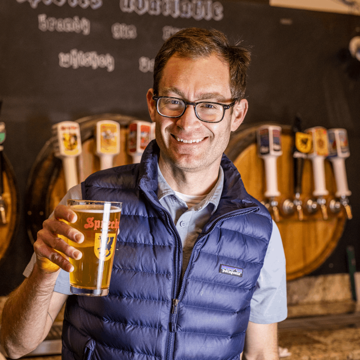 Man holding pint of beer in a Sprecher pint glass and smiling