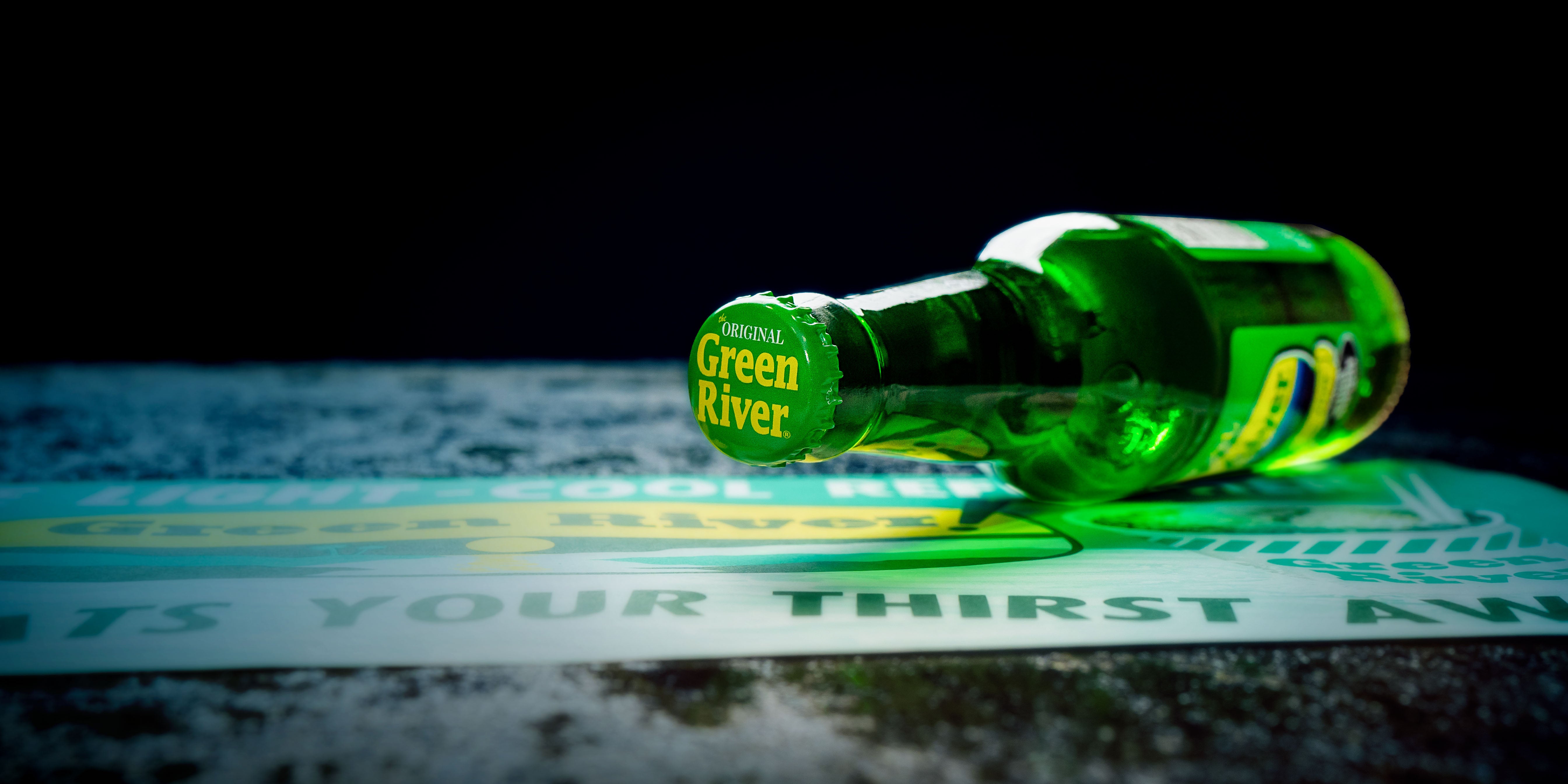 A bottle of Green River Soda on its side with the bottle cap facing forward