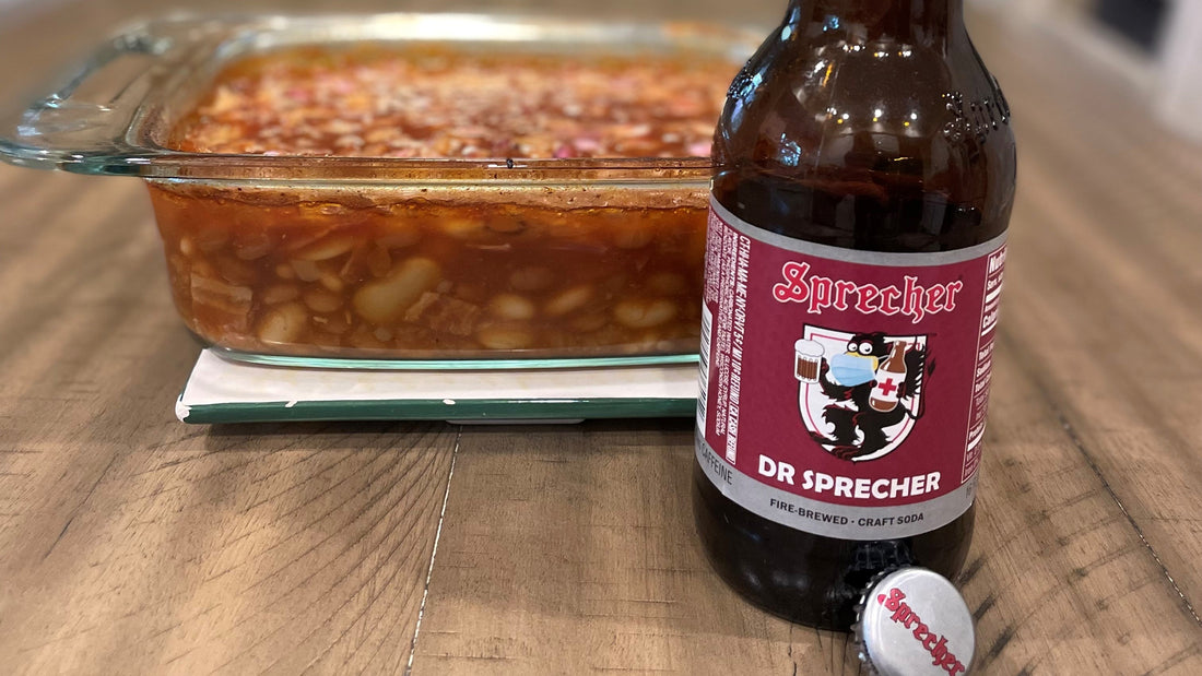 A glass pan of Dr Sprecher baked beans with a bottle of Dr Sprecher in the foreground