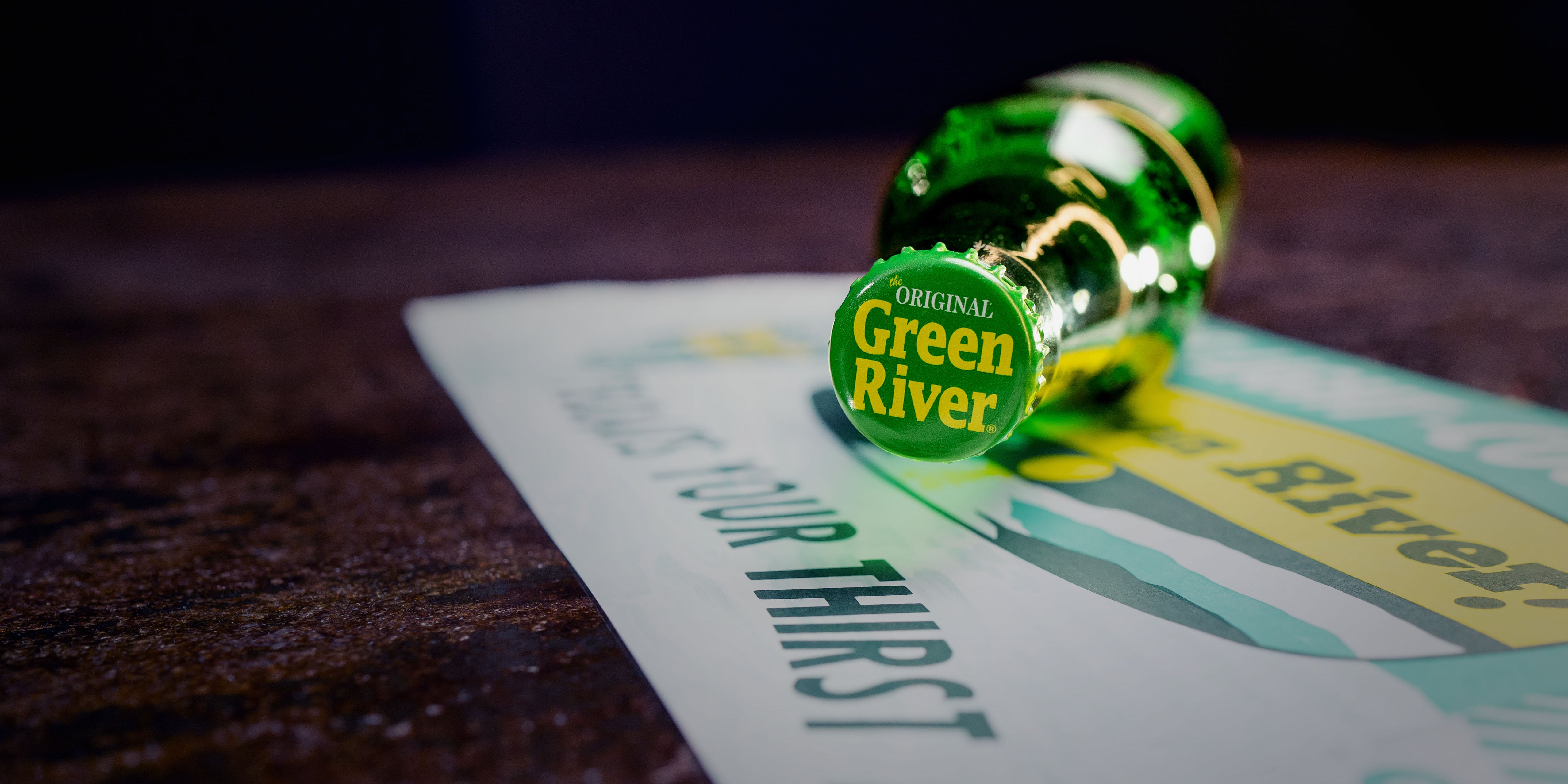 An Irish Shandy cocktail with bottles of Green River and Abbey Triple in the background