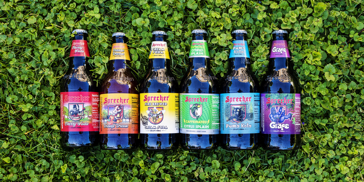 A rainbow of sprecher soda bottles in the grass