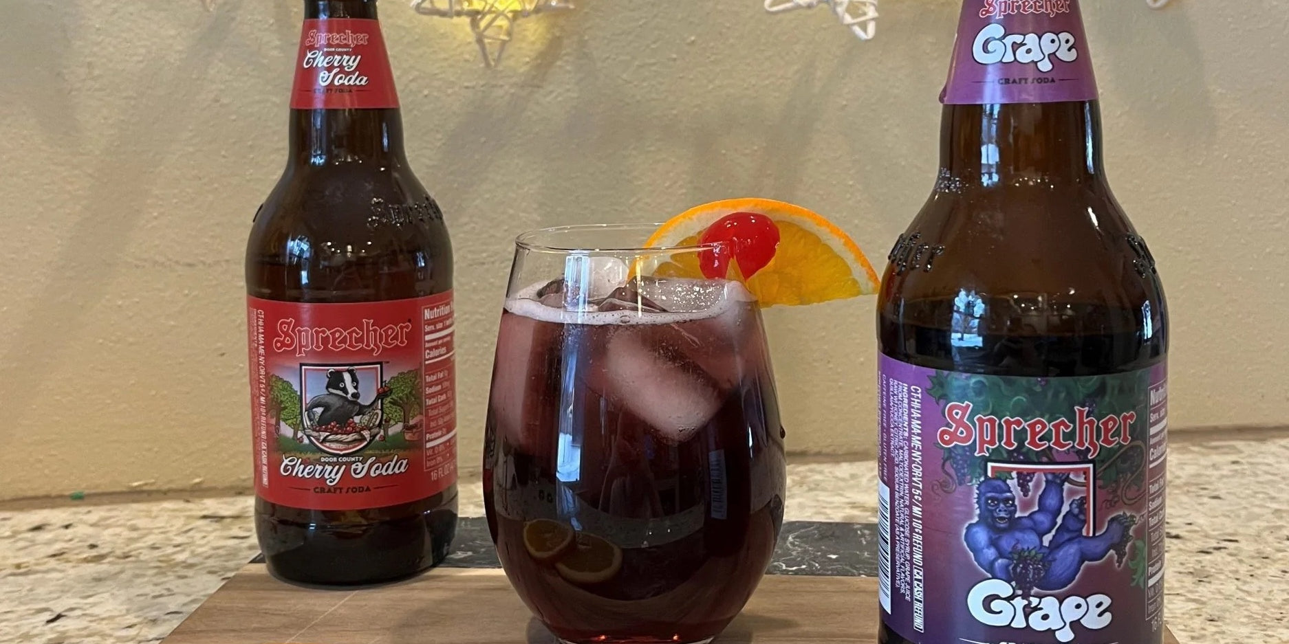 Sprecher Sangria Mocktail with orange slices and grape soda in the foreground and cherry soda in the background