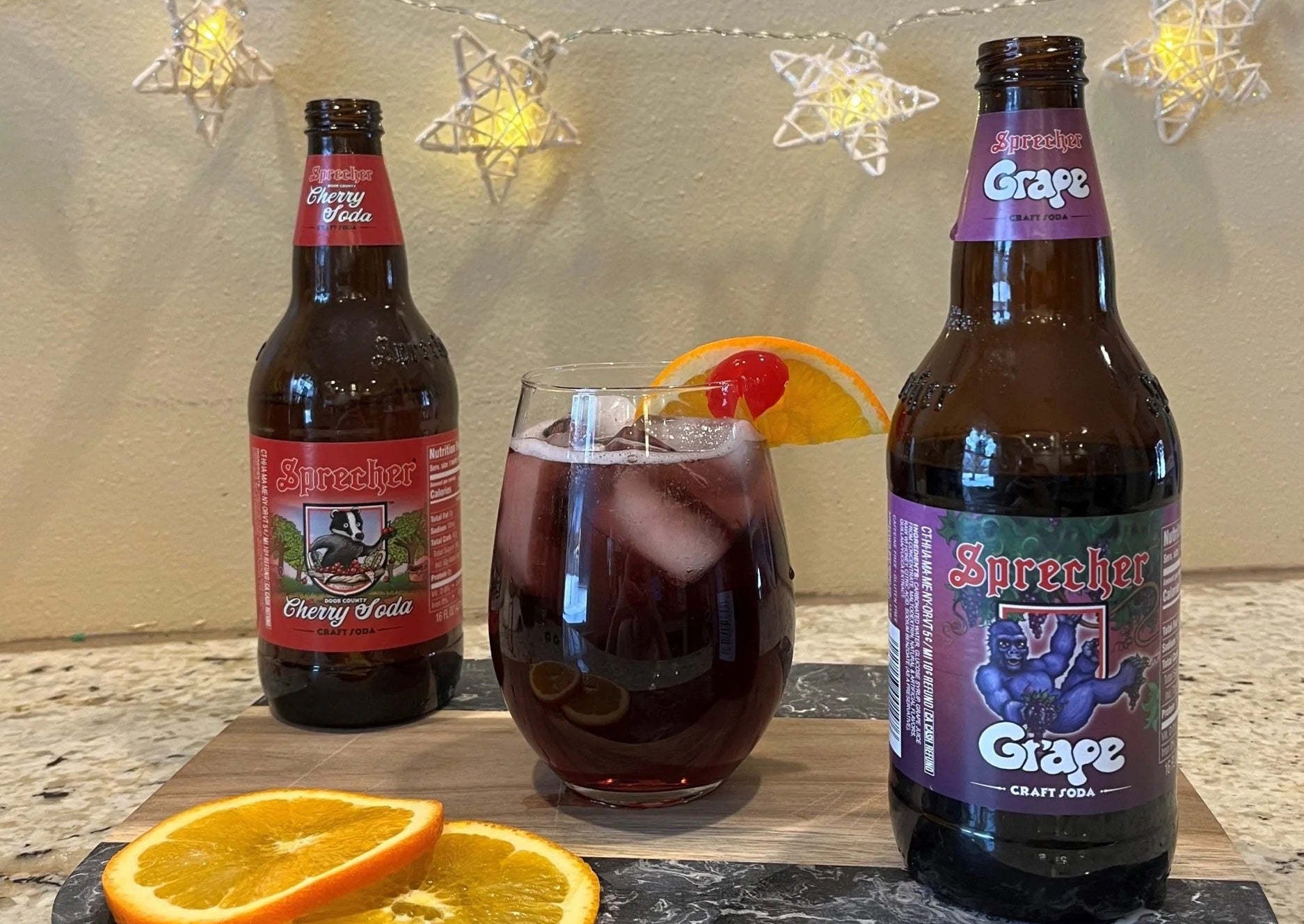 Sprecher Sangria Mocktail with orange slices and grape soda in the foreground and cherry soda in the background