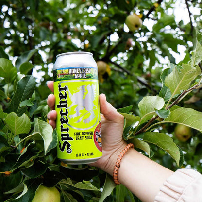 A 16oz can of Fire-Brewed Sprecher Honeycrisp Apple craft soda being plucked from an apple tree