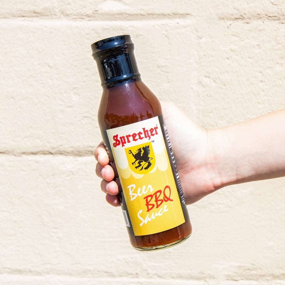 A hand holding a bottle of Sprecher Beer BBQ Sauce