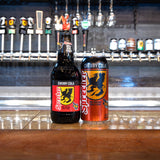 Two bottles of Cherry Cola on a bar counter with beer taps in the background