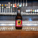 Bottle of cherry soda on a bar counter with beer taps in the background