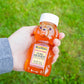 Kallas Farms 100% natural pure honey held in front of a green grass background