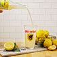 A bottle of Sprecher Lemonade being poured into a pint glass while surrounded by lemons