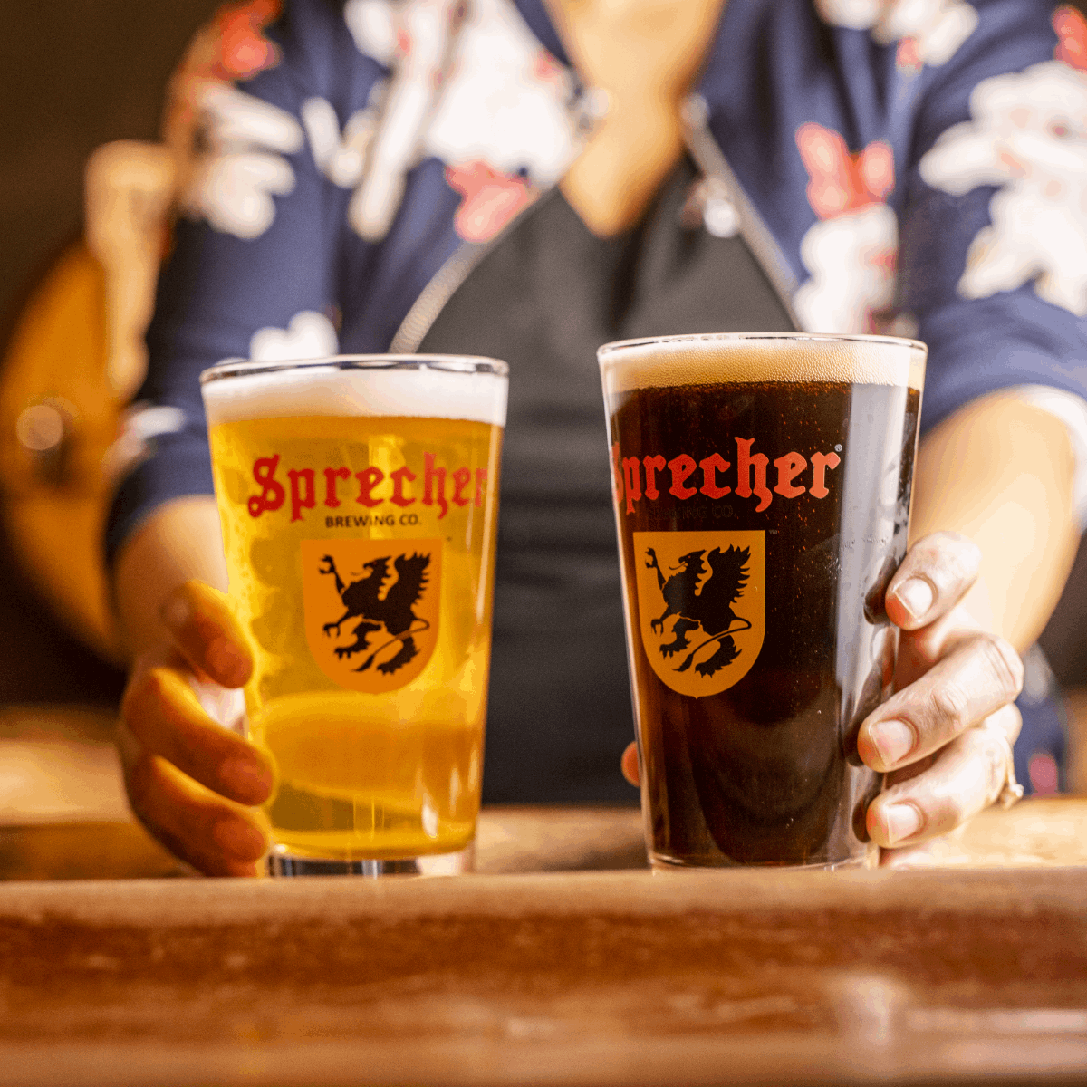 Bartender serving two pint glasses on a bar