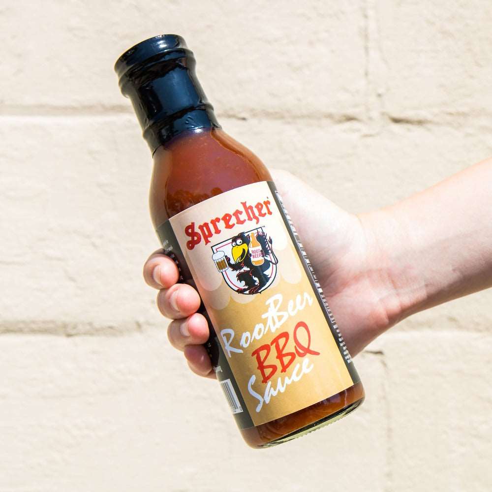 Someone holding a bottle of Sprecher Root Beer BBQ Sauce