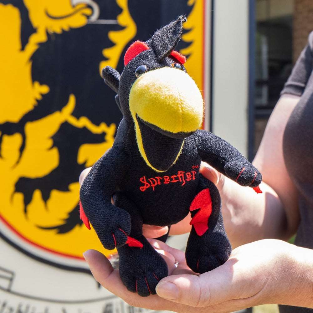 Someone holding a Sprecher Plush Rooty Doll in front of the Sprecher Sign.