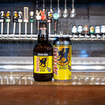 Two bottles of Sprecher Cream Soda on a bar counter with beer taps in the background.