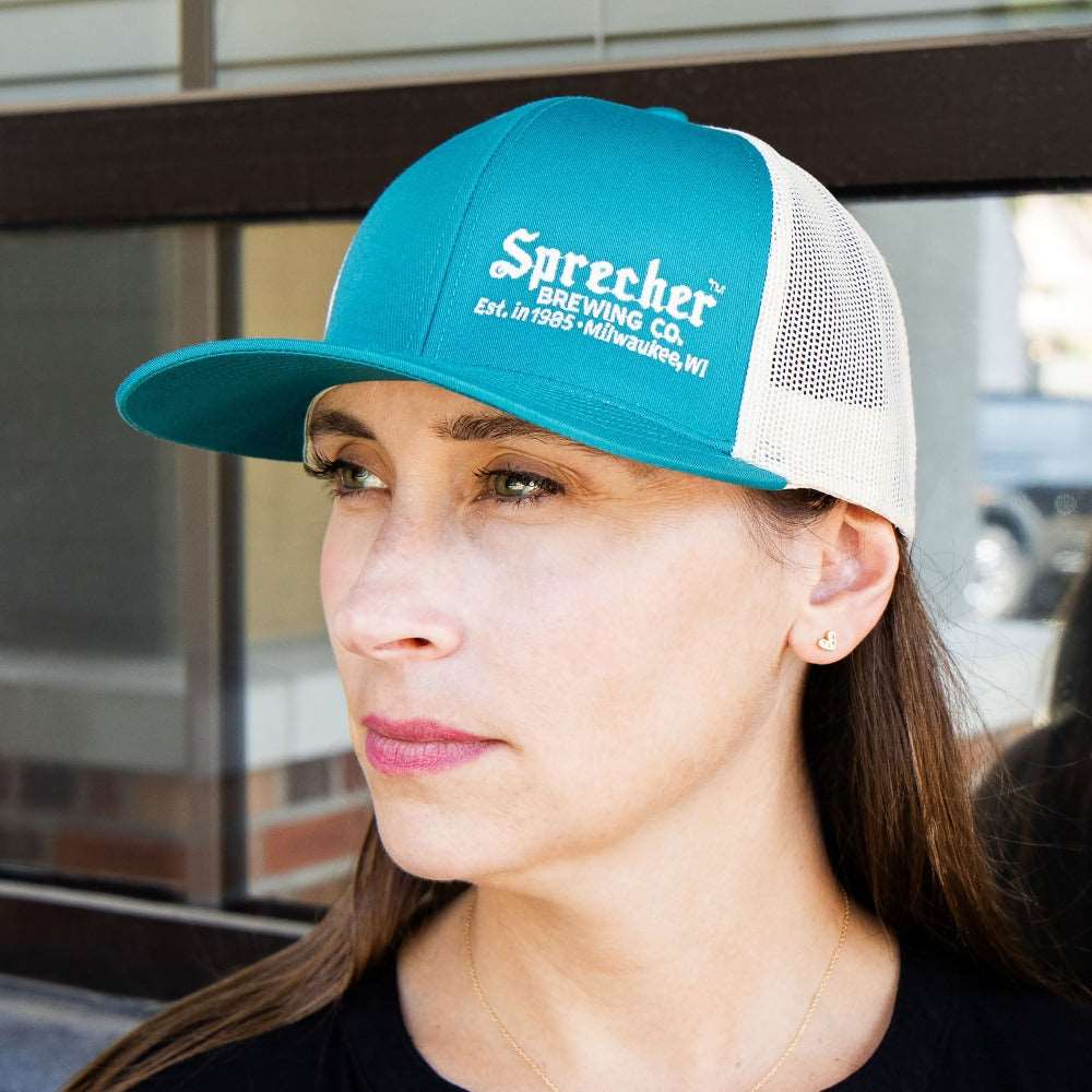 A woman wearing a Sprecher Teal trucker hat