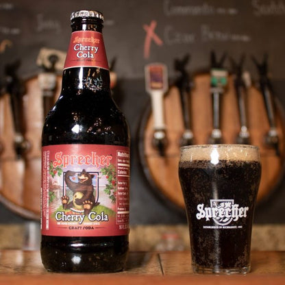A 16oz bottle of Sprecher Cherry Cola on a bar next to a glass of cherry cola