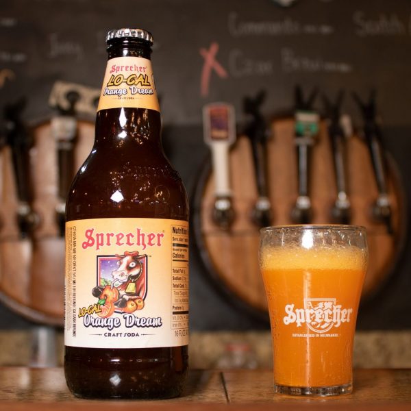 A 16oz bottle of Sprecher Lo Cal Orange Dream next to a glass of Lo Cal Orange Dream on a bar