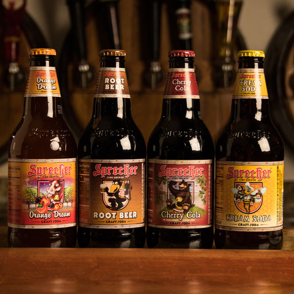Sprecher Orange Dream, Root Beer, Cherry Cola, and Cream Soda bottles next to each other on a bar